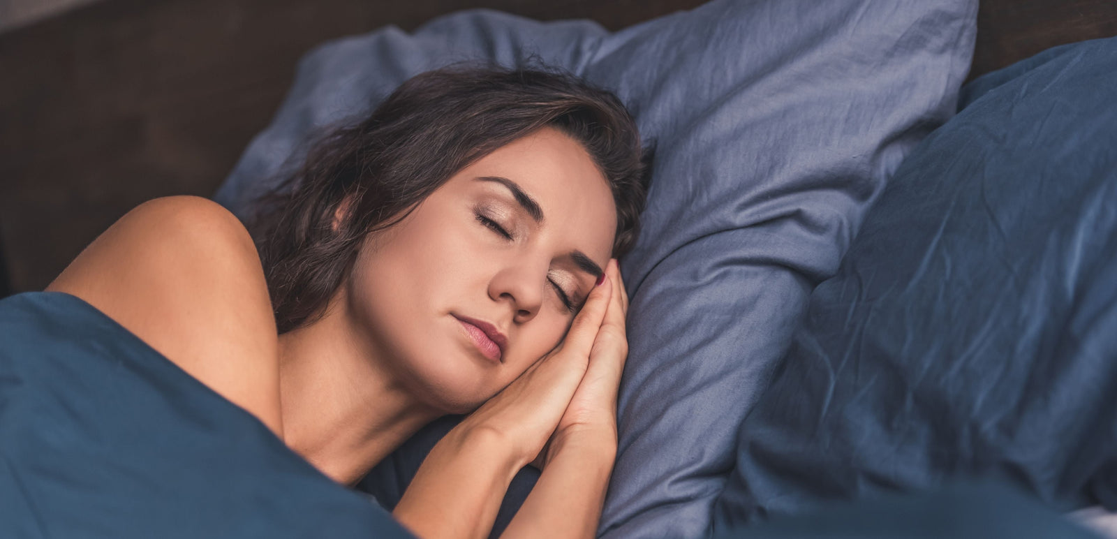 Woman sleeping peacefully with blue pillows and blanket