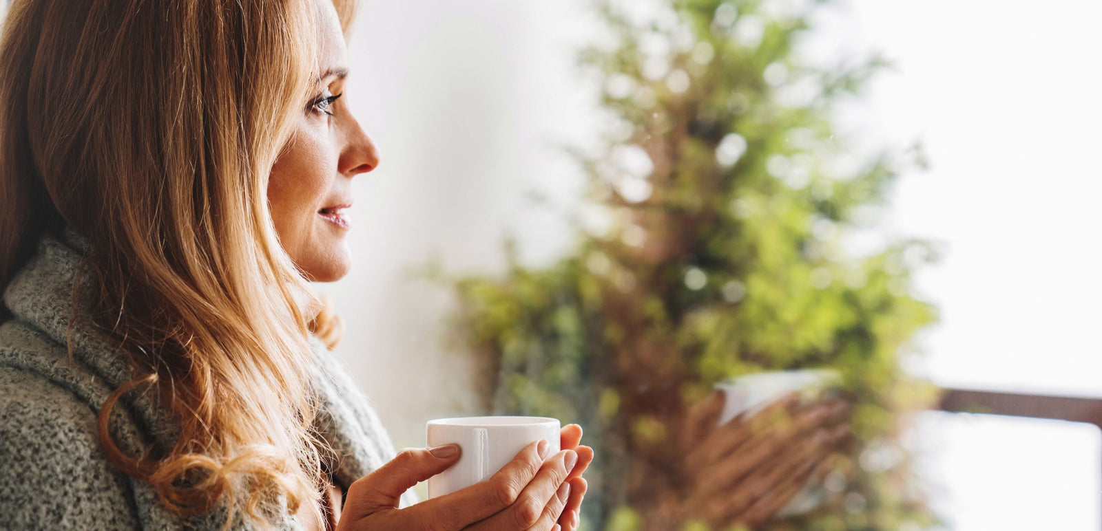 Woman wrapped in blanket with a hot mug of tea