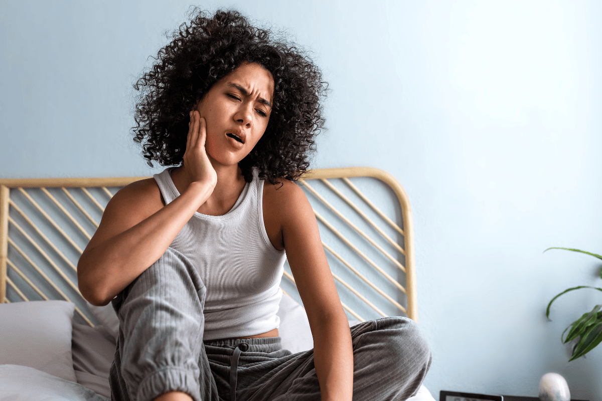 woman rubbing her jaw because of TMJ and how to stop your teeth from grinding at night